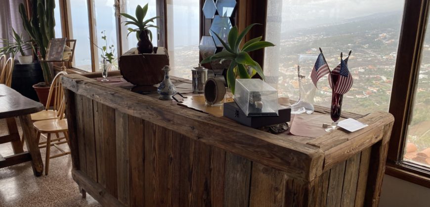 A house with a garden and a restaurant with panoramic views of the ocean and the city.